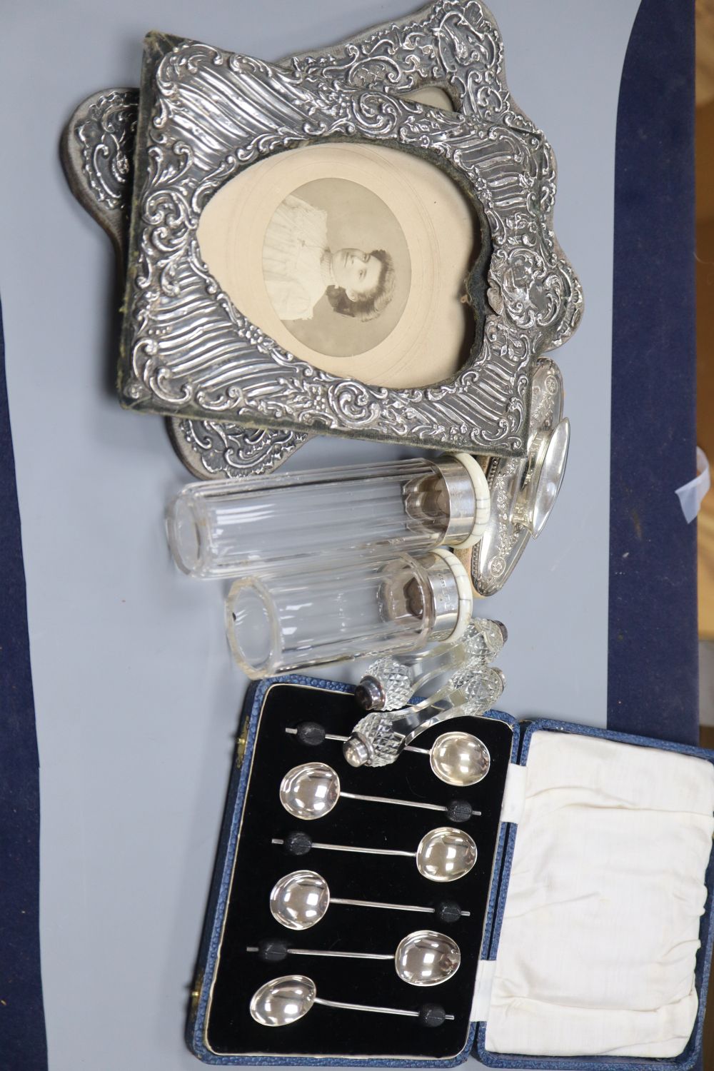 Two early 20th century silver photo frames, a cased set of 6 silver coffee spoons, a silver mounted buffer, knife rests and two ivory t